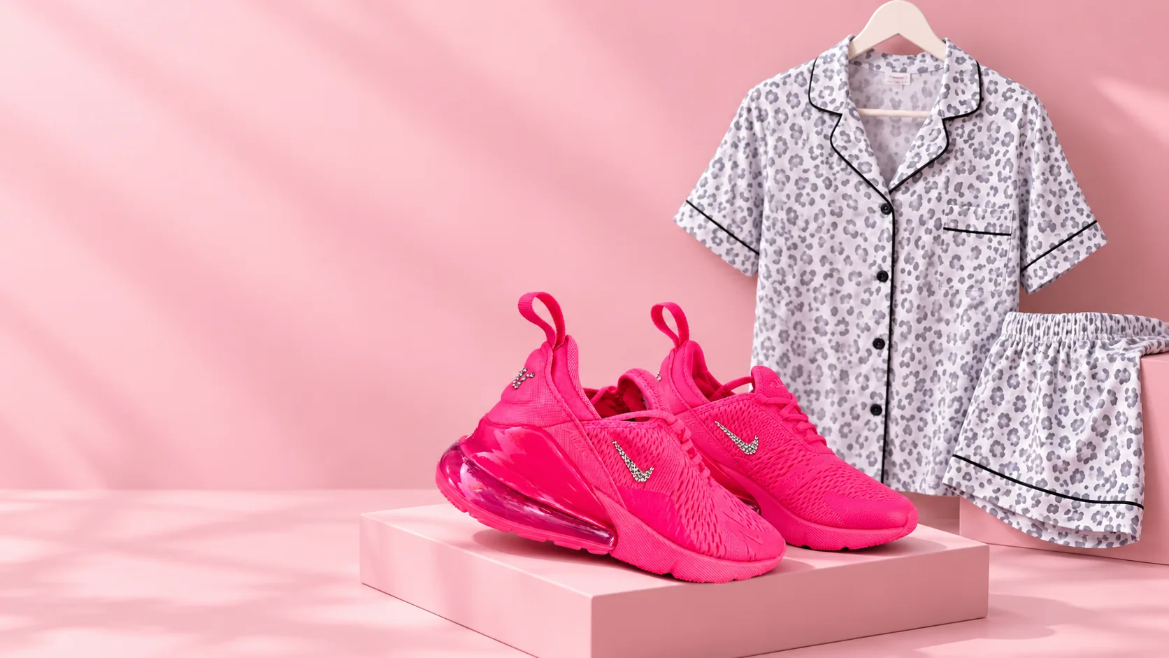 Pink Nike Air Max sneakers displayed with a women's cheetah print pajama set on a pink background